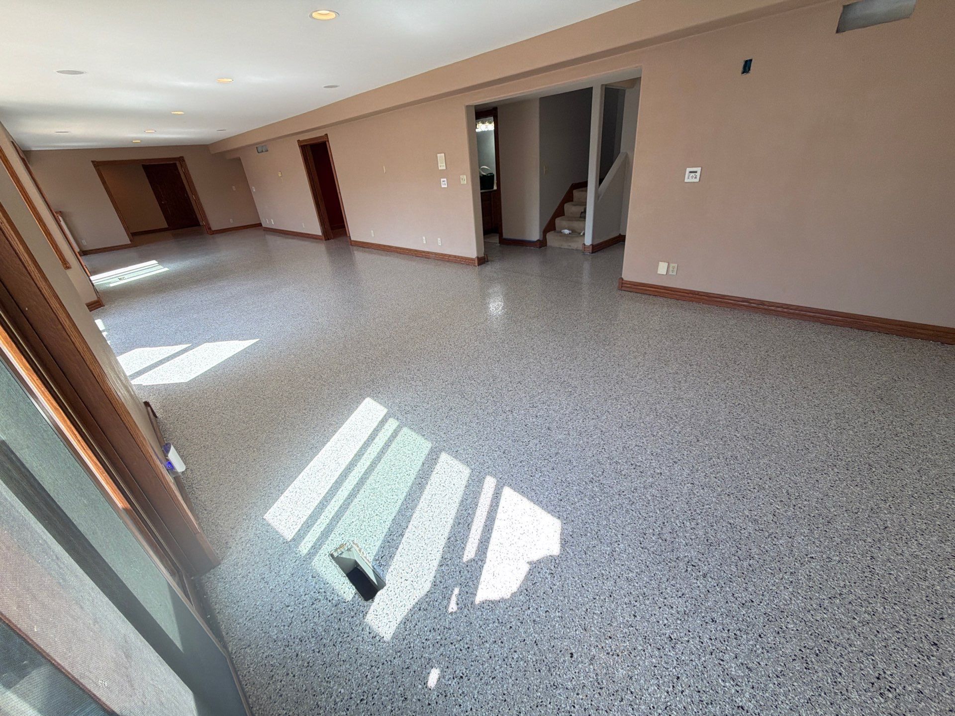 Empty beige room with tiled floor and sunlight streaming through a window onto the wall and floor