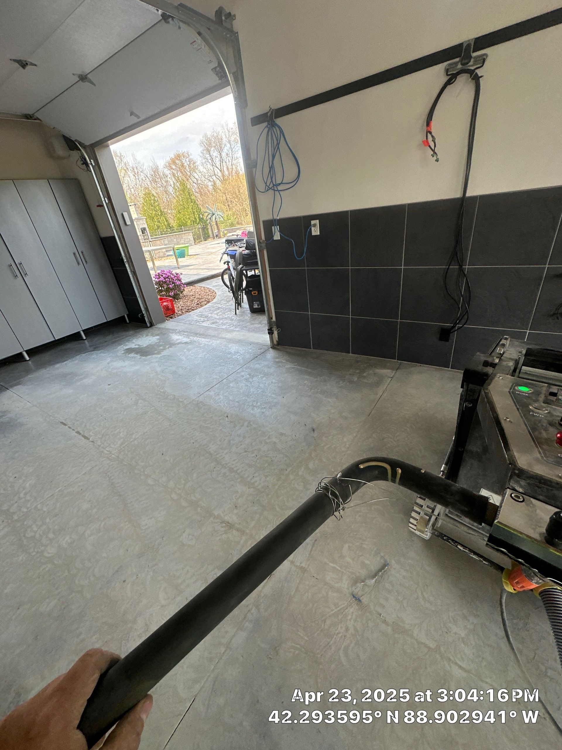 Garage interior with open door, black cabinets, and a bicycle visible outside.