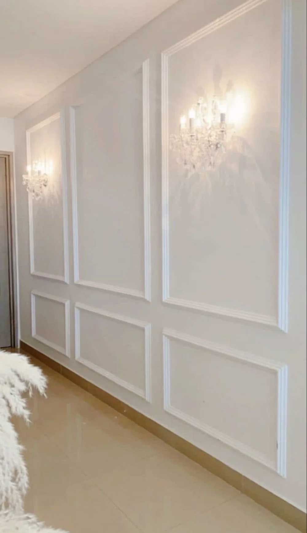 White wall with decorative molding and sconces, modern hallway.