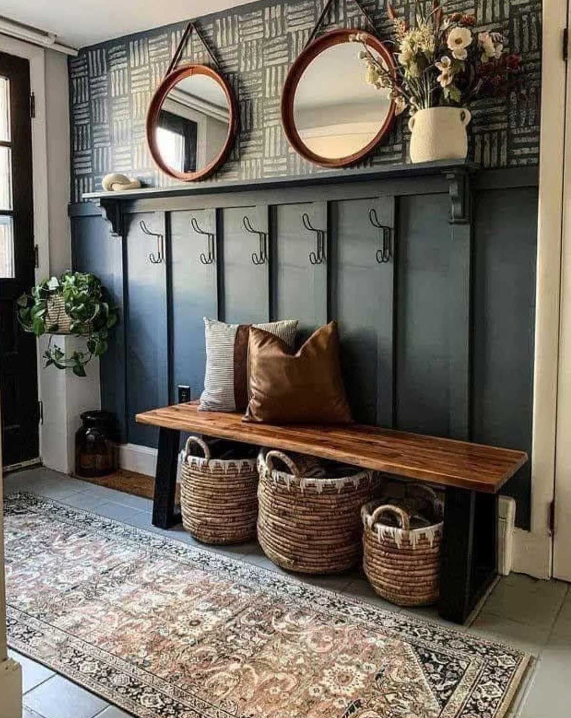 Hallway with dark blue paneling, bench, baskets, round mirrors, and patterned rug.