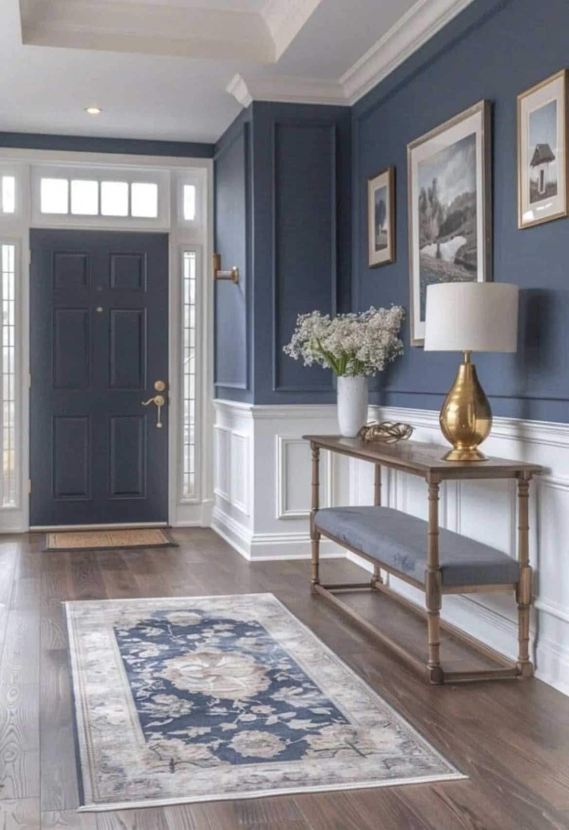 Blue foyer with dark blue door, white trim, console table, floral rug, and framed artwork.