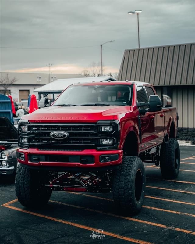 A red ford truck is parked in a parking lot.