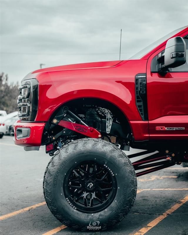 A red truck with black wheels is parked in a parking lot.