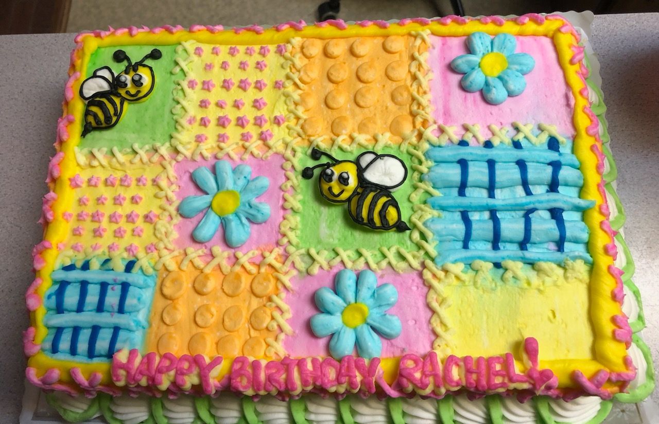 Colorful decorated birthday cake with bees, flowers, and “Happy Birthday Rachel” icing text