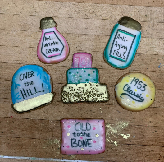 Hand-painted retro pills and bottles on wood, with labels like “Old to the Bone” and “1953 Classics.”