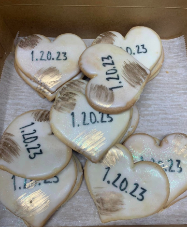 Heart-shaped decorated cookies on a tray, each printed with a different date in black icing.