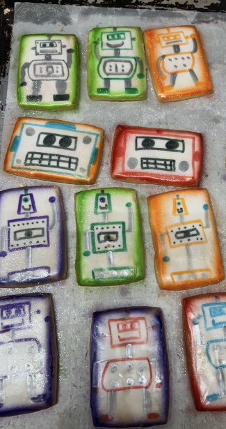 Colorful hand-drawn robot sketches on paper arranged in a grid, with white, green, orange, purple, and blue backgrounds