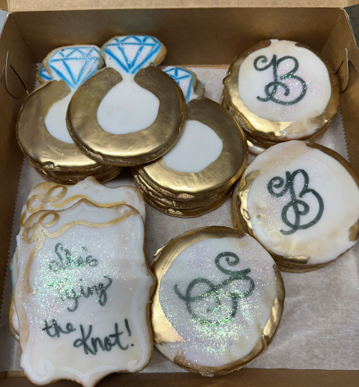 Decorated cookies in a box, with blue diamond accents and monogram designs in white and gold icing