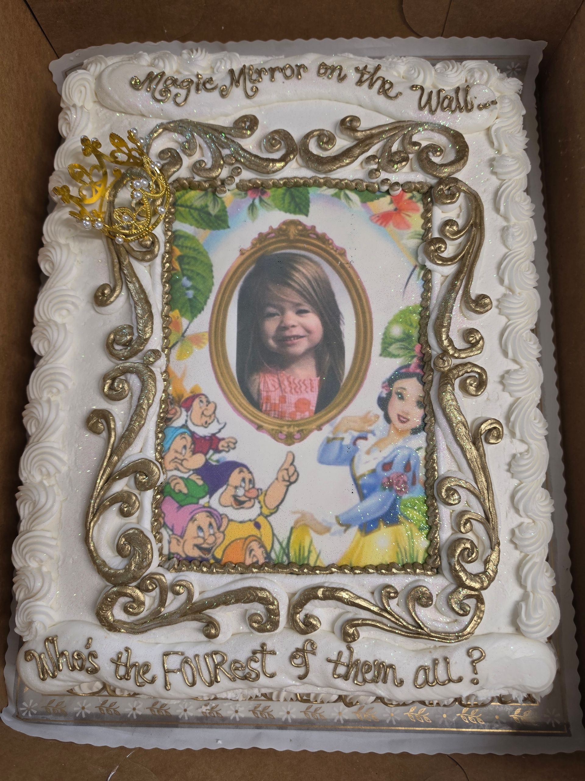 Decorated cake with a child’s portrait framed by ornate icing and cartoon princesses