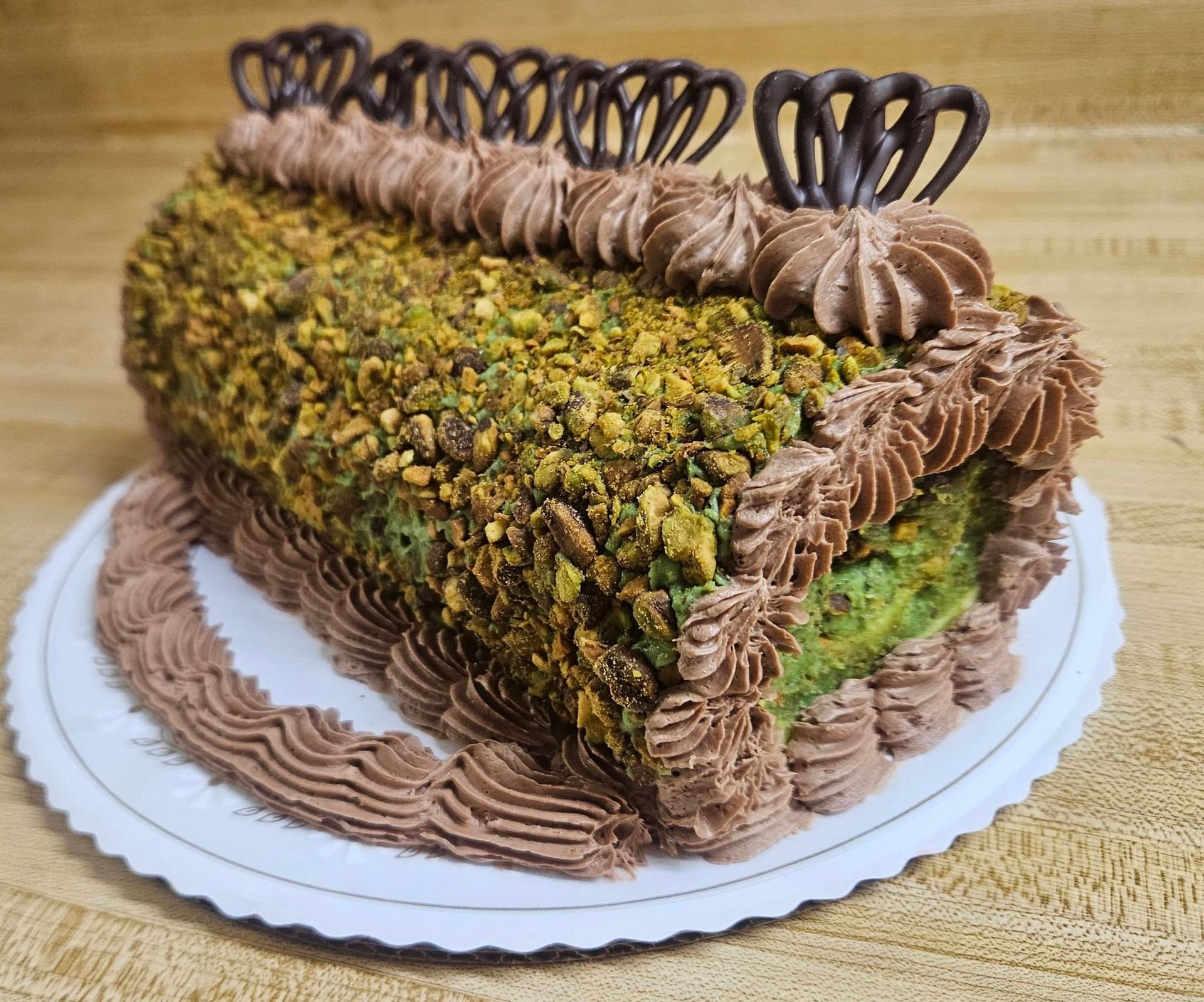 Pistachio-topped chocolate cake with piped frosting