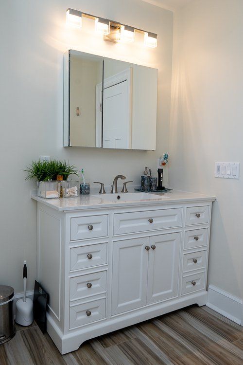 A bathroom with a white vanity , sink , mirror and toilet.