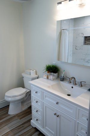 A bathroom with a toilet , sink and mirror.
