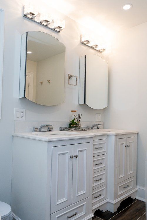 A bathroom with two sinks , a mirror and a toilet.