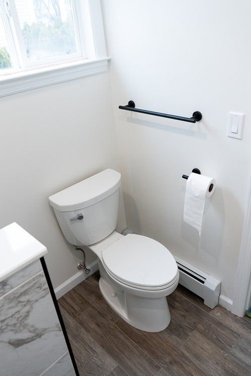A bathroom with a toilet , sink , and window.