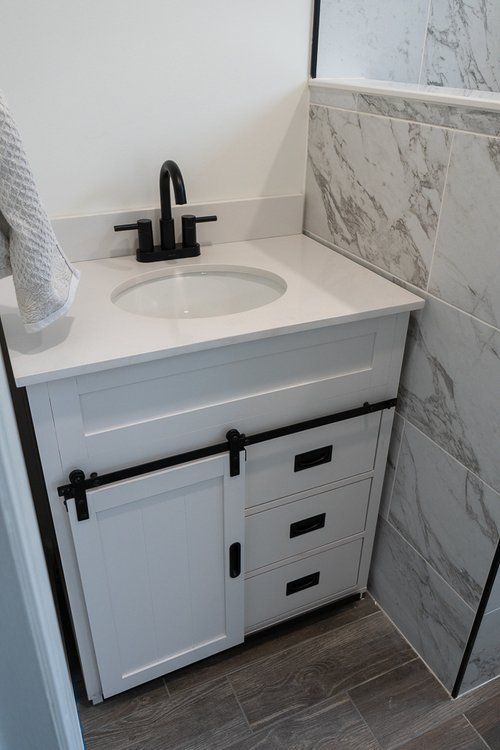 A bathroom vanity with a sink , faucet and drawers.