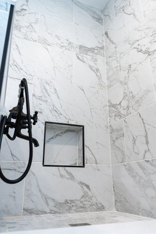 A bathroom with marble tiles , a tub and a shower.