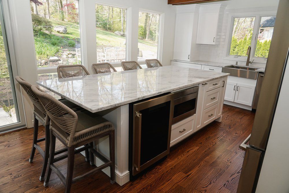 A kitchen with a large island , stools and a refrigerator.
