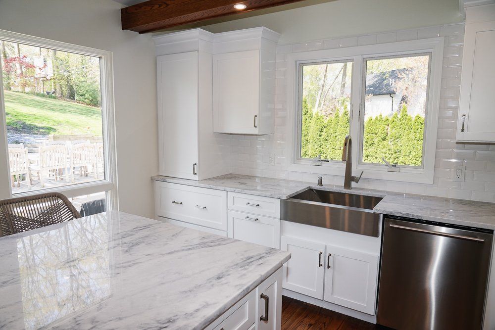 A kitchen with white cabinets , stainless steel appliances , a sink , and a large island.