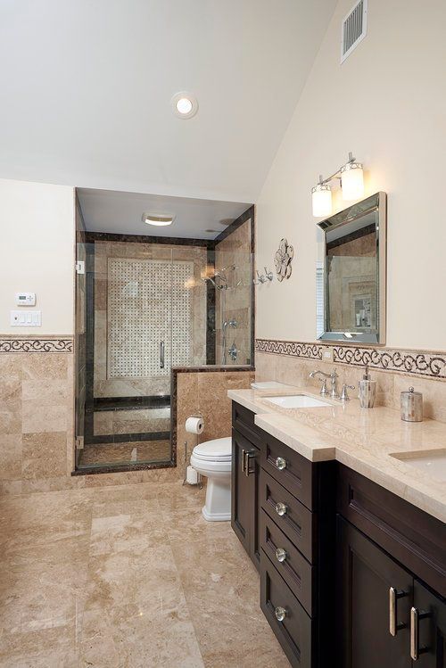 A bathroom with two sinks , a toilet , and a walk in shower.