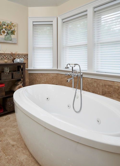 A bathroom with a large white tub and a window