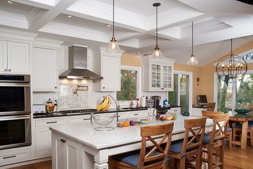 A kitchen with white cabinets , stainless steel appliances , and a large island.