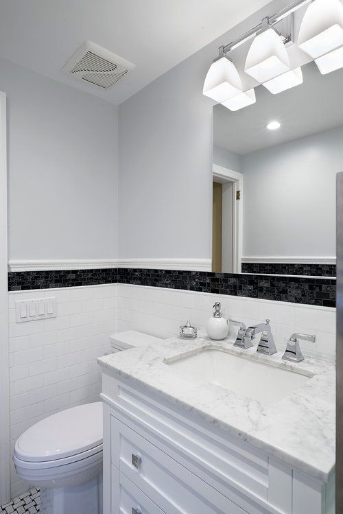 A bathroom with a toilet , sink and mirror.