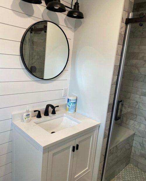 A bathroom with a sink , mirror and shower.