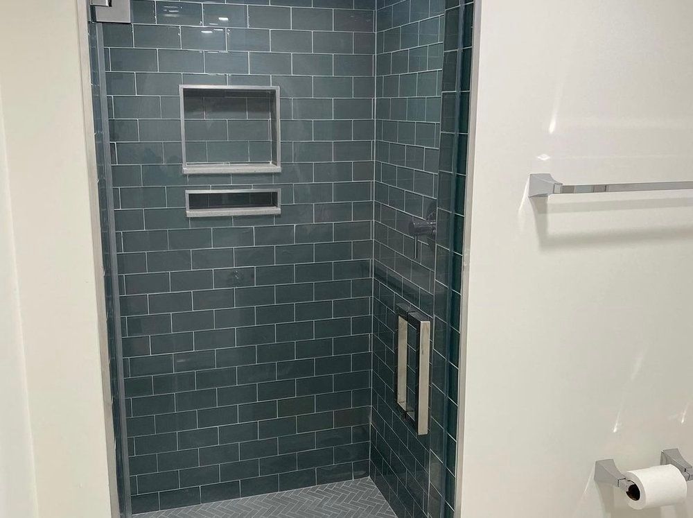 A bathroom with a walk in shower and a toilet paper holder