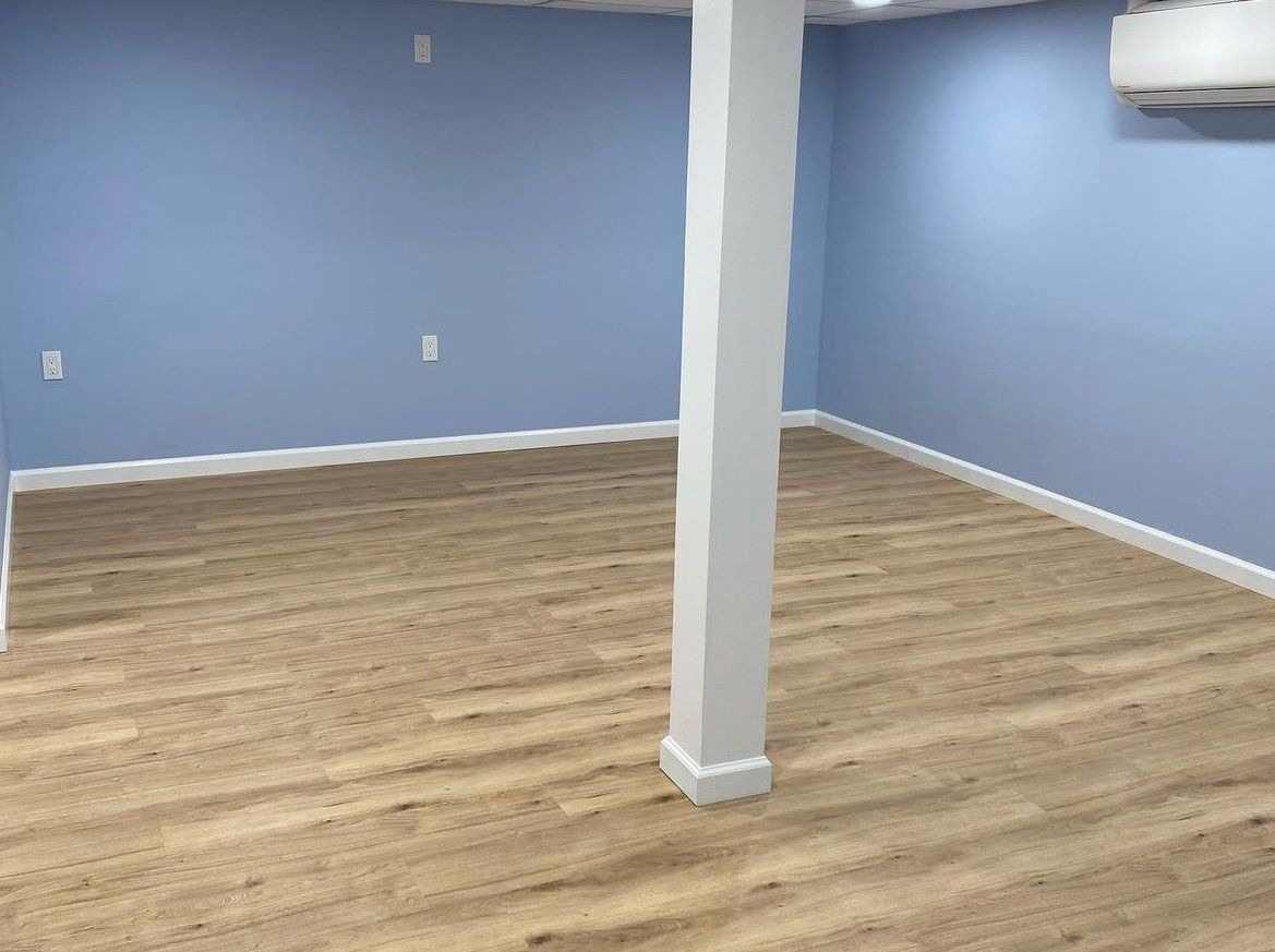 An empty room with a wooden floor and blue walls.