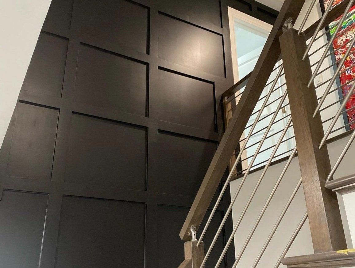 A staircase with a black wall and a stainless steel railing
