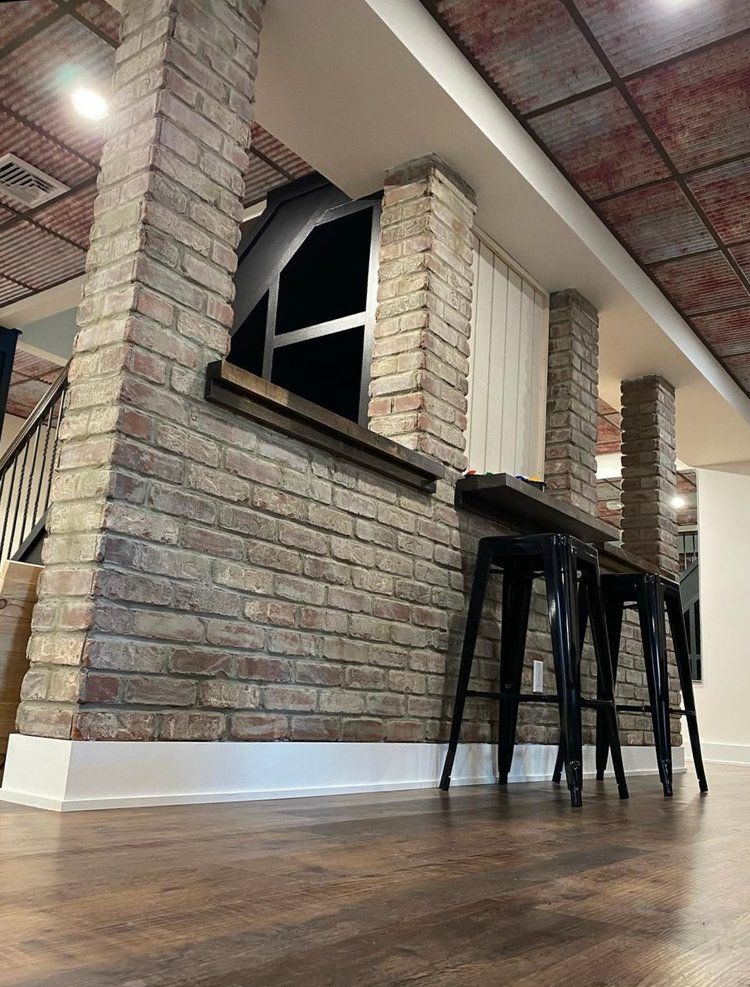 A room with a brick wall and stools in front of it.