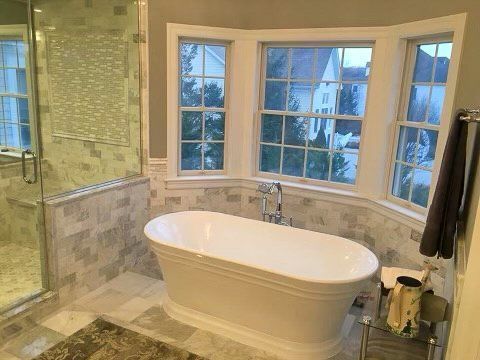 A bathroom with a bathtub , shower , and bay window.
