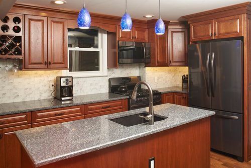 A kitchen with stainless steel appliances , granite counter tops , and wooden cabinets.
