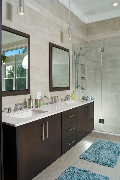 A bathroom with two sinks , two mirrors and a walk in shower.