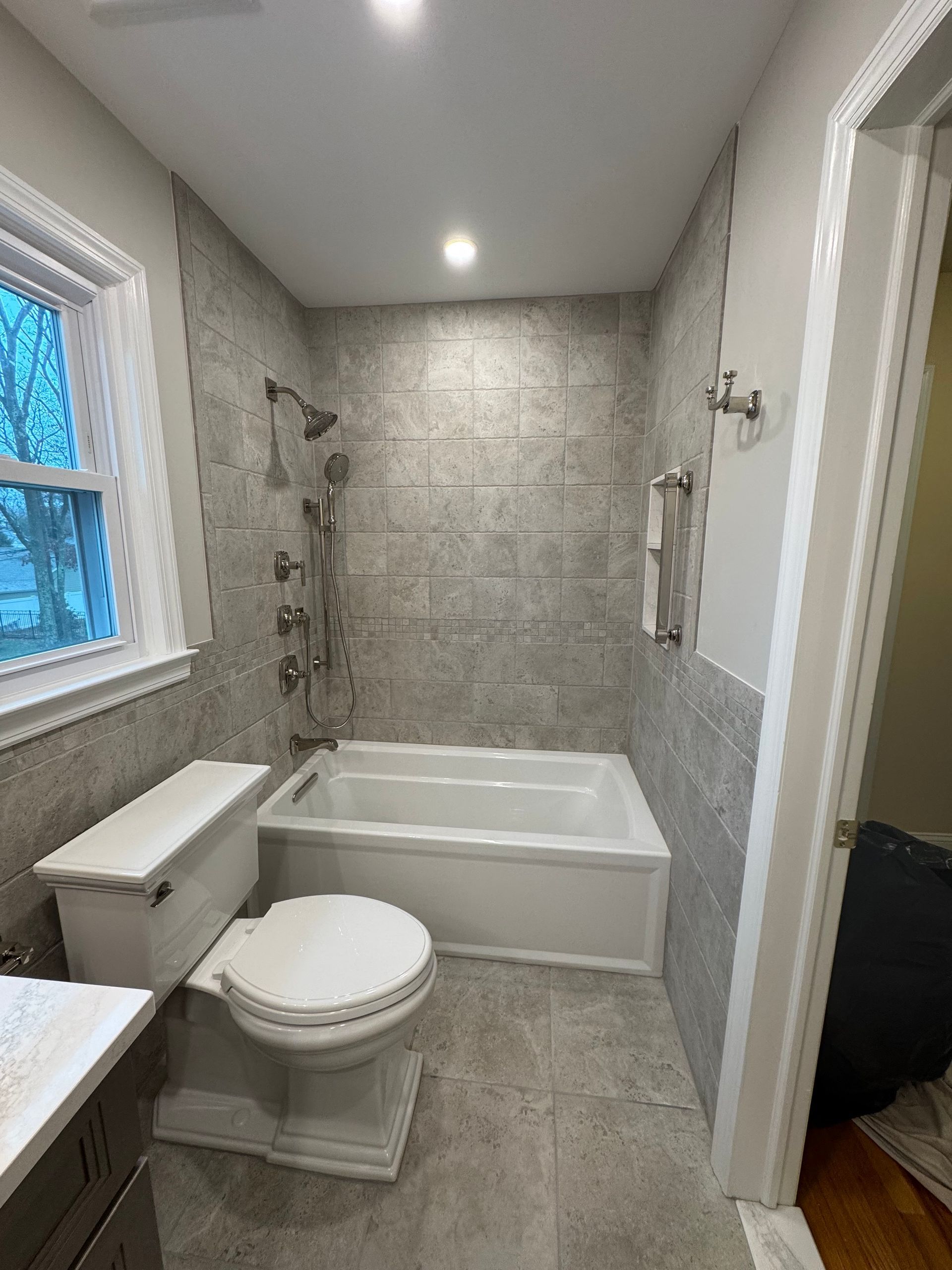 A bathroom with a toilet, tub, shower, and window.