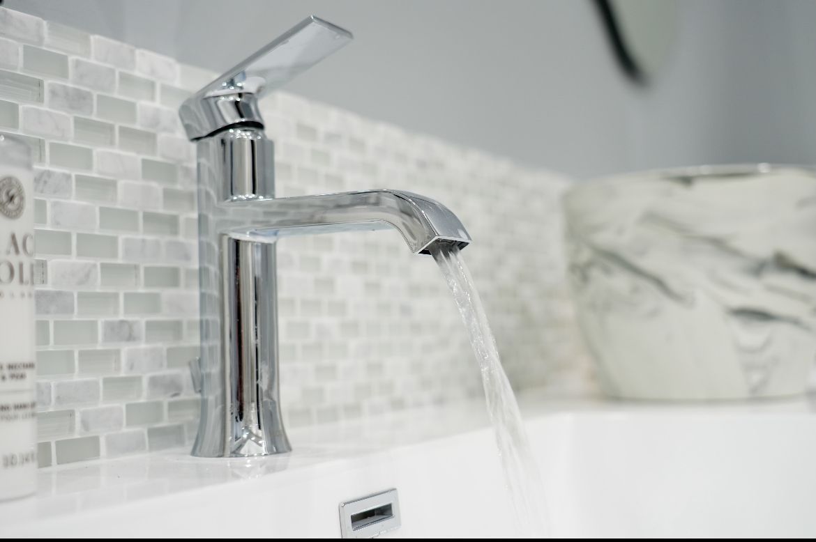 A bathroom sink with a faucet and towels hanging on the wall.
