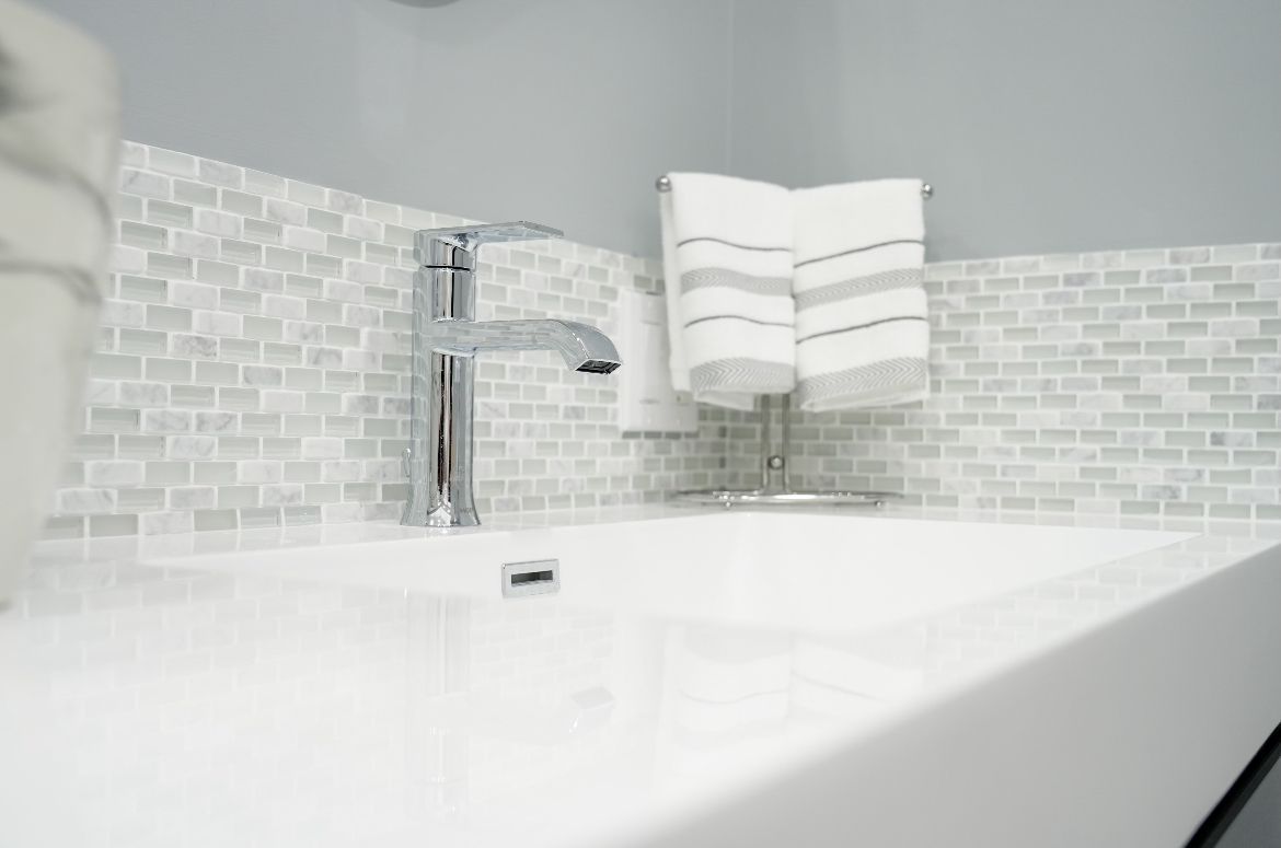 A bathroom sink with a faucet and towels hanging on the wall.