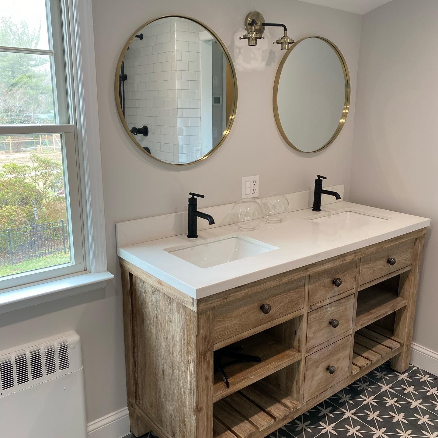 A bathroom with two sinks , two mirrors and a window.