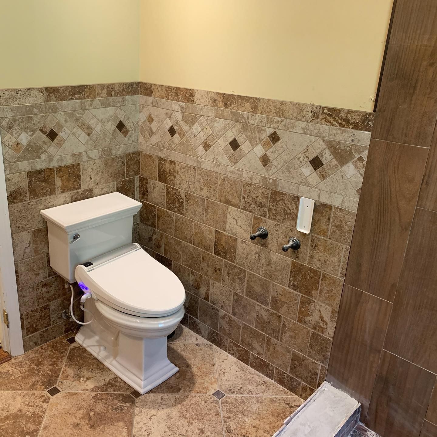 A toilet in a bathroom with a tiled wall