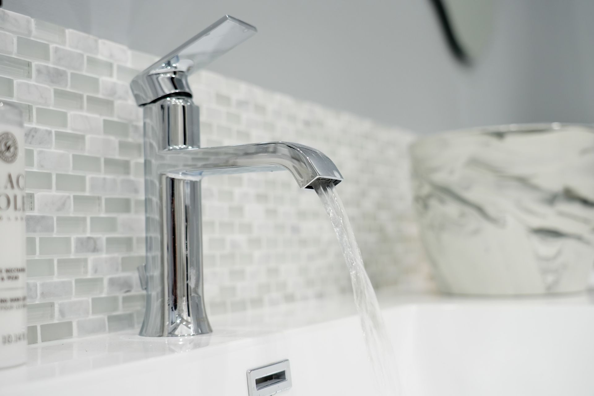 A bathroom sink with water running from a chrome faucet.