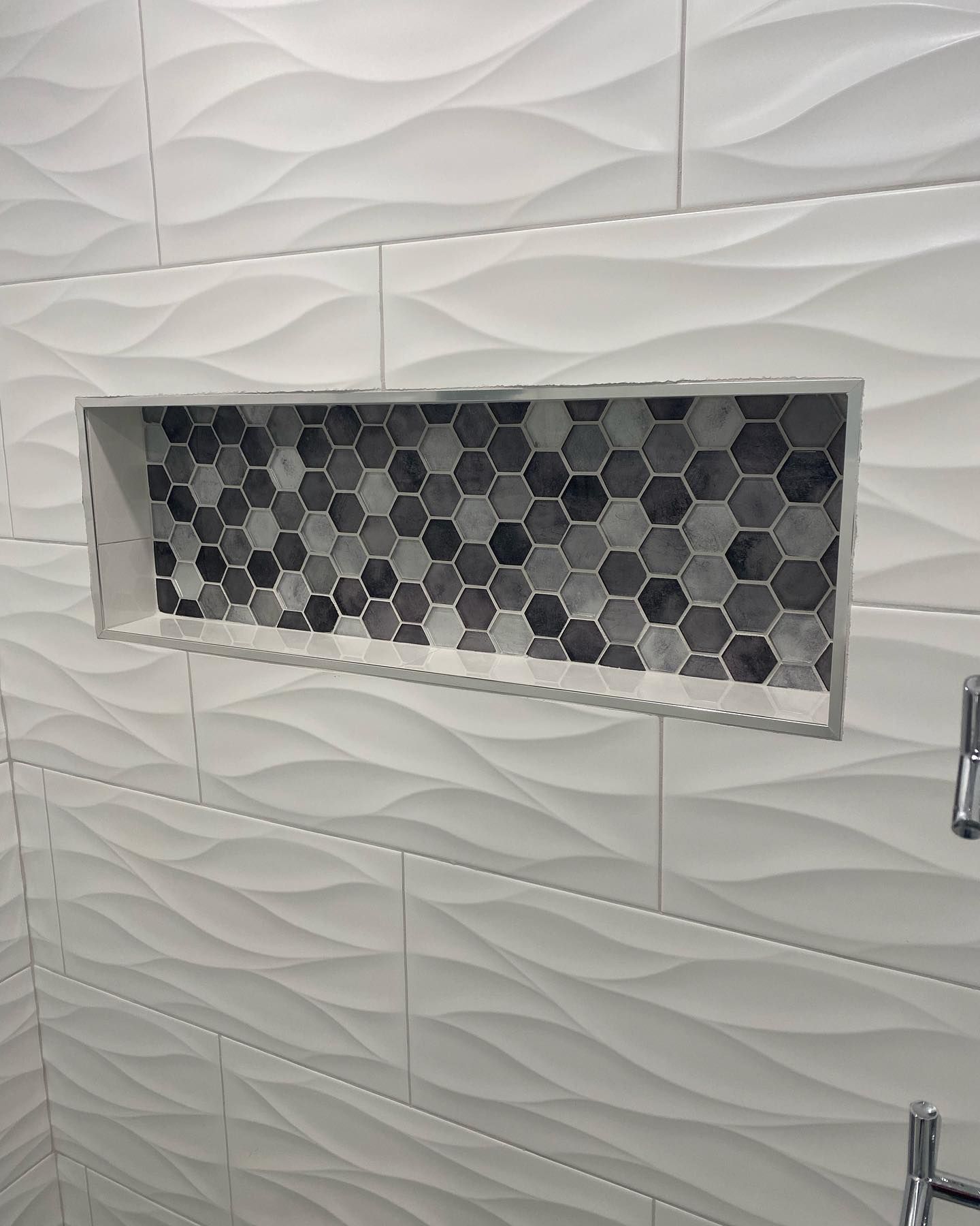 A shower niche in a bathroom with black and white tiles.