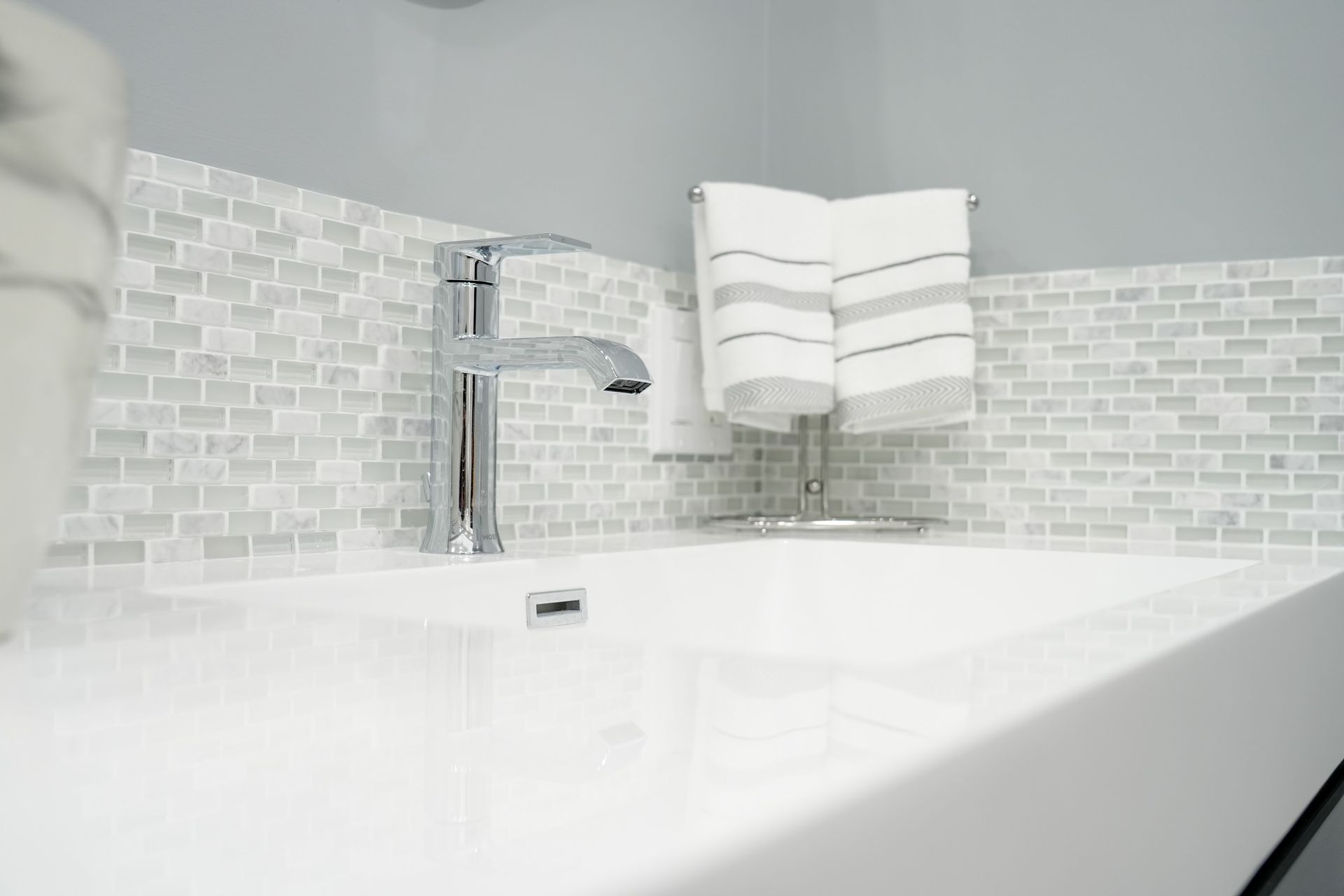 A bathroom sink with a faucet and two towels hanging on the wall.