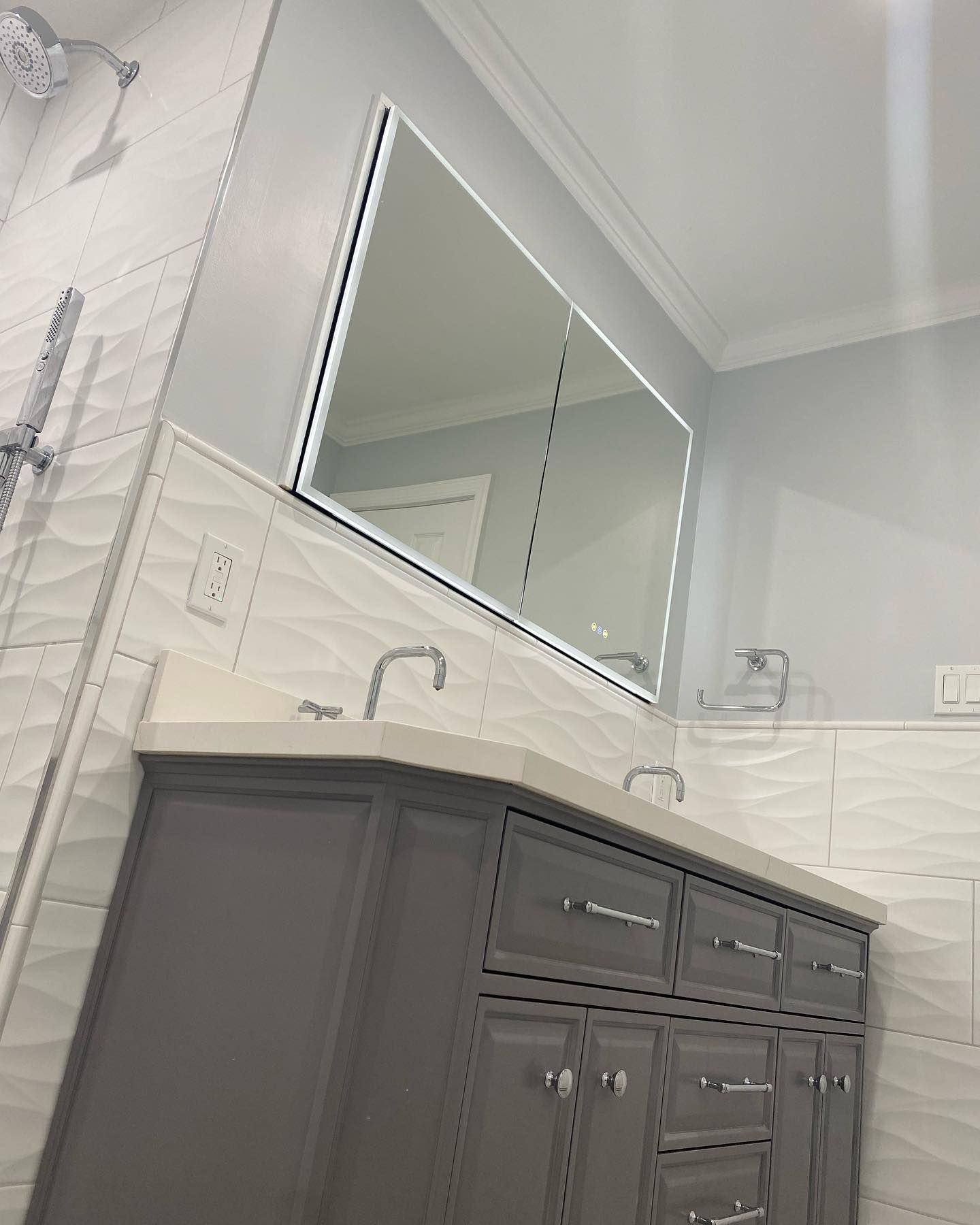 A bathroom with a vanity , sink , mirror and shower.