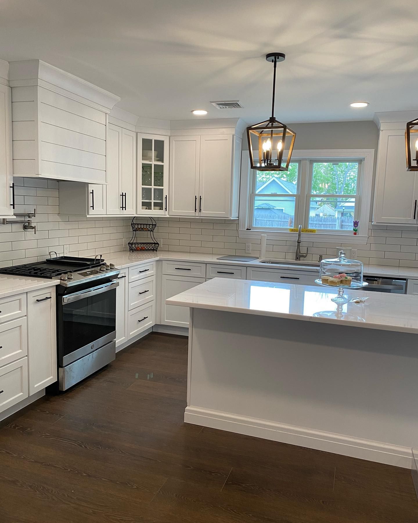 A kitchen with white cabinets , stainless steel appliances , and a large island.