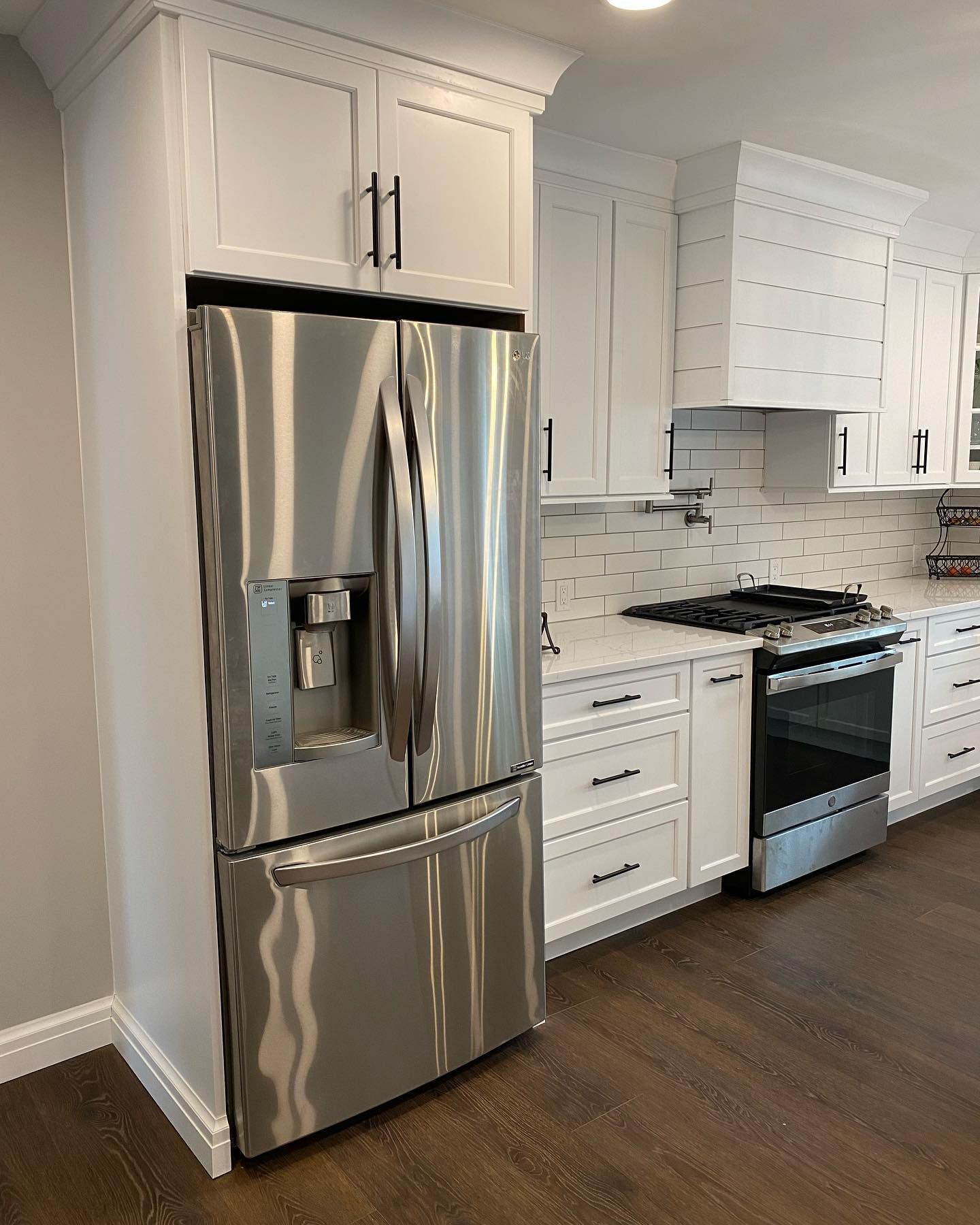 A kitchen with stainless steel appliances and white cabinets.