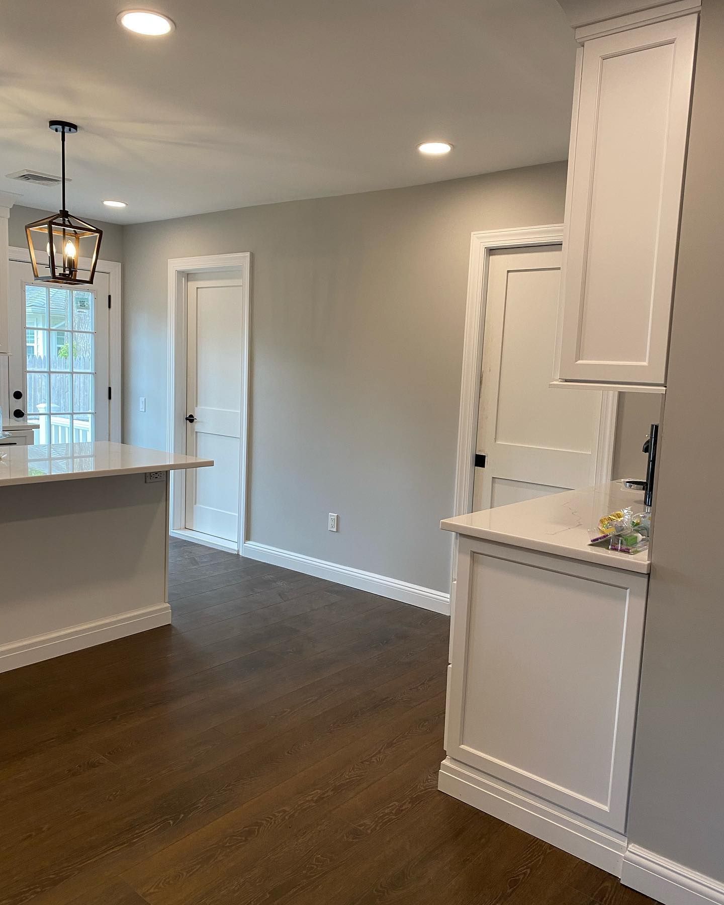 An empty kitchen with white cabinets and wooden floors.
