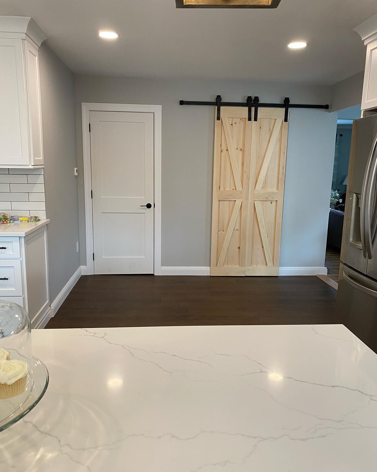 A kitchen with a sliding barn door and a refrigerator.