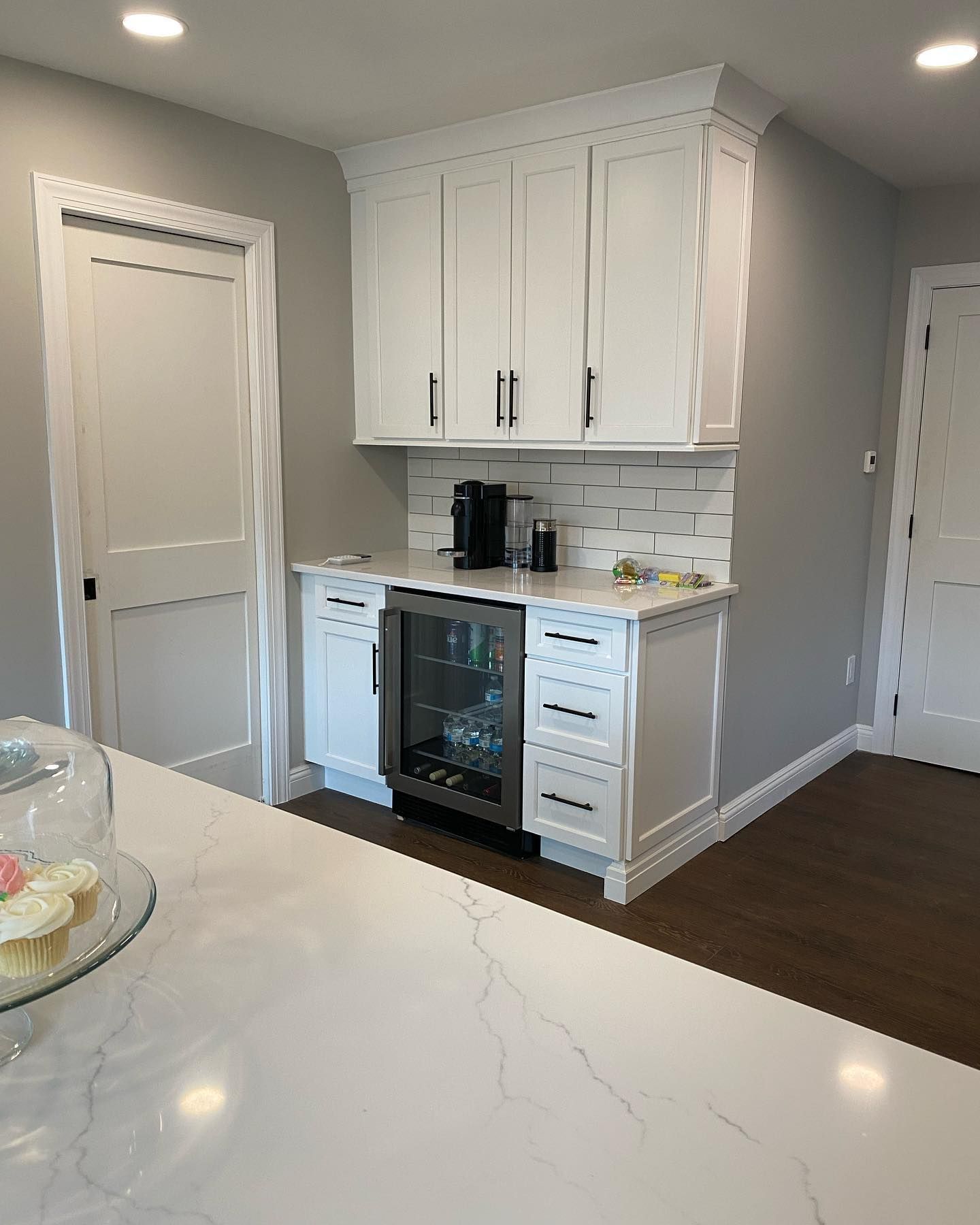 A kitchen with white cabinets and a stainless steel refrigerator.