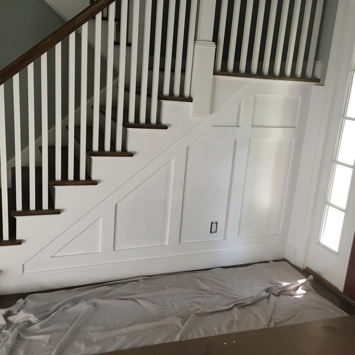 A white staircase with a wooden railing in a room