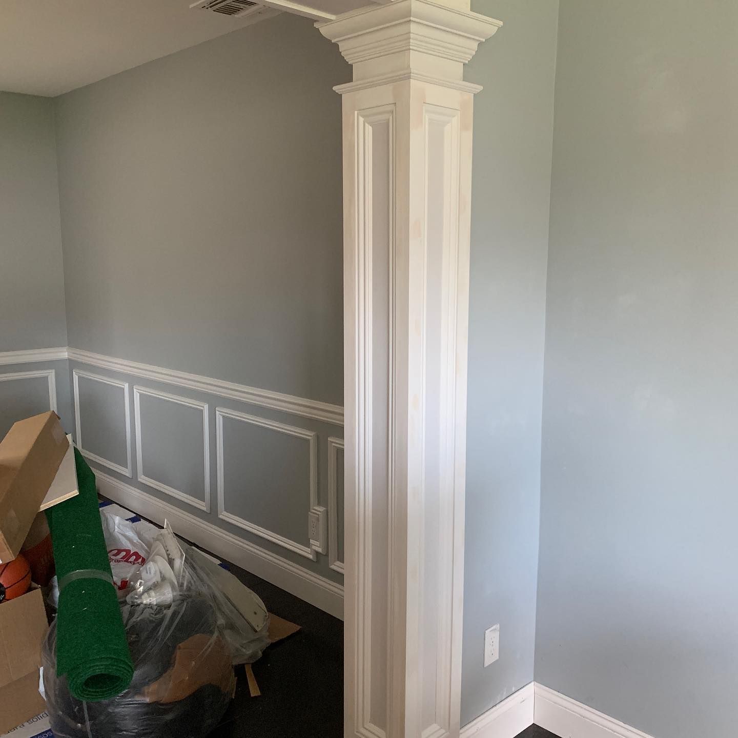 A room with a white column and boxes on the floor.